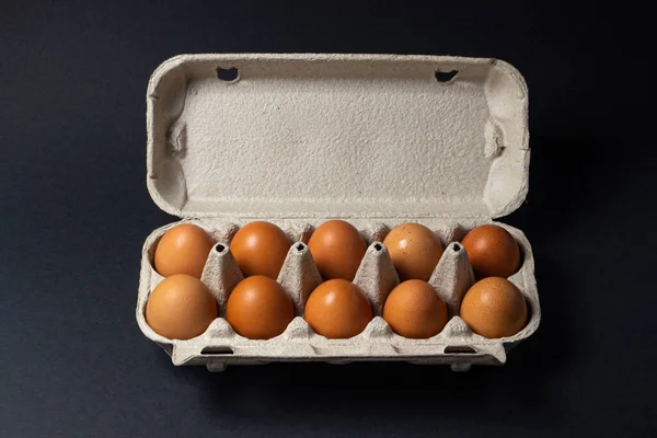 Eggs on a black background. Chicken eggs in a paper box