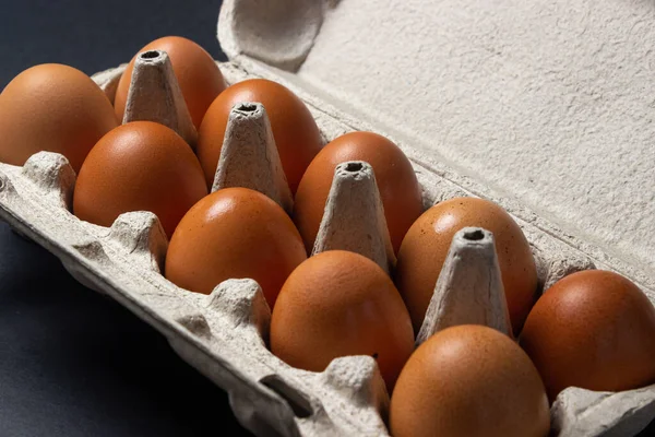 Eggs on a black background. Chicken eggs in a paper box