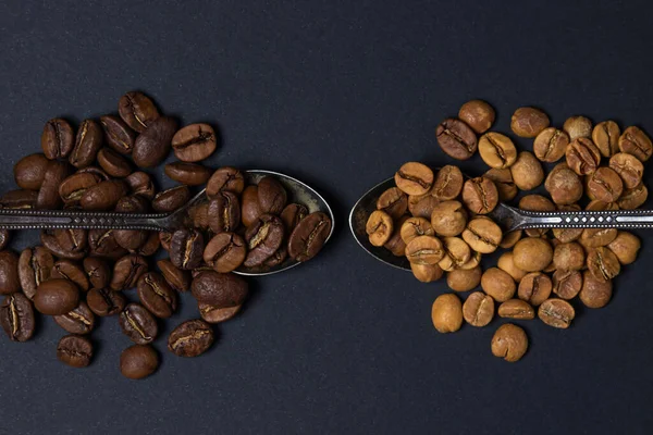 Siyah arka planda kahve çekirdekleri. Kahve çekirdekli iki kaşık. Bir kaşık dolusu kahvenin içinde