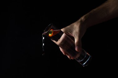 Siyah arka planda bir bardak suda acı biber. Erkek el bir bardak su tutuyor.