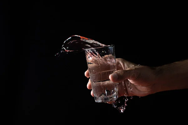 Water on a black background. water is poured out of the glass. Pure water