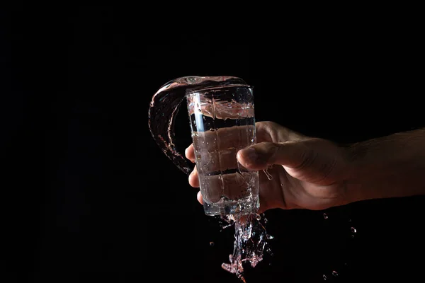 Water on a black background. water is poured out of the glass. Pure water