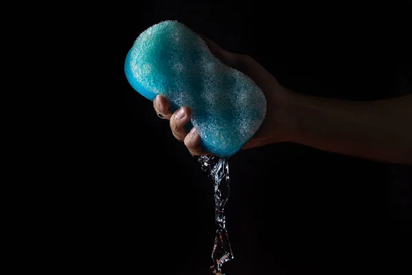 Water on a black background. Water is squeezed out of the bath sponge. Pure water