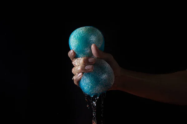 Water on a black background. Water is squeezed out of the bath sponge. Pure water