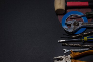 Siyah arka planda çalışan araçlar. Ev geliştirme ya da onarım projeleri için kullanılmış ve kirli iş araçları. El emeği konsepti. Yazıt ya da logo için bir yer var.