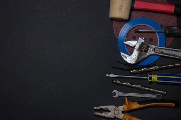Working tools on a black background. Used and dirty work tools for home improvement or diy repair projects. Manual labor concept. There is a place for an inscription or logo