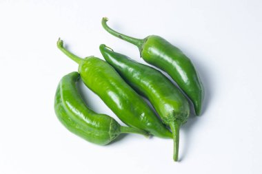 Beyaz arka planda yeşil acı biber. Birkaç yeşil acı biber yan yana yatıyor. Sağlıklı sebzeler