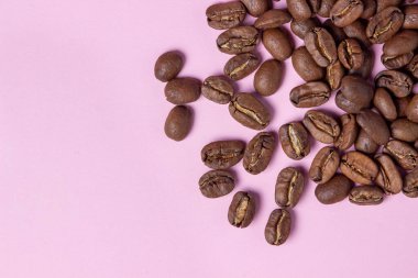 Pembe arka planda kahve çekirdekleri. Kahve konsepti.