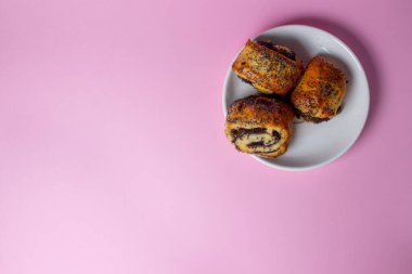 Pembe arka planda haşhaş tohumlu rulo. Ev yapımı pişirme. Tatlı hamur işleri