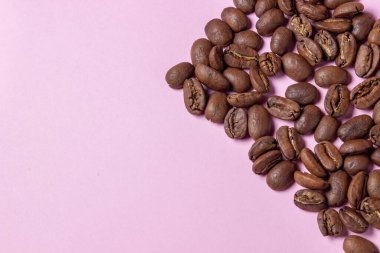 Pembe arka planda kahve çekirdekleri. Kahve konsepti.