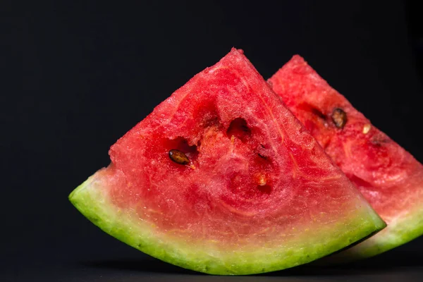 Watermelon on a black background. Cut off a slice of watermelon. Red ripe watermelon