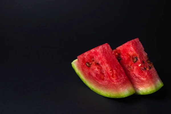 Watermelon on a black background. Cut off a slice of watermelon. Red ripe watermelon