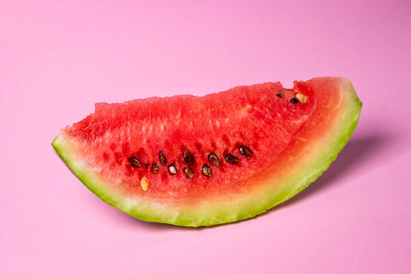 Watermelon on a pink background. Cut off a slice of watermelon. Red ripe watermelon