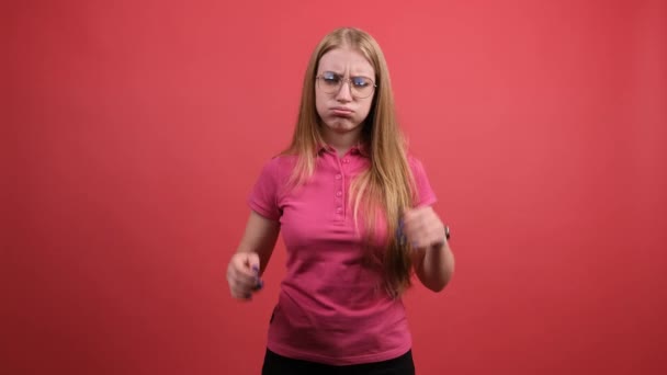 Kırmızı stüdyo arka planında kafası karışmış bir kadın el ele tutuşuyor.. — Stok video