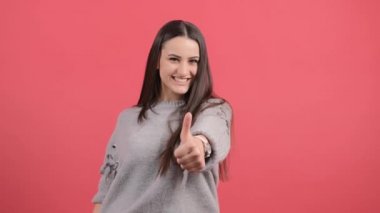 Güzel bir kadın kırmızı arka planda izole edilmiş, baş parmak hareketi gösteriyor..