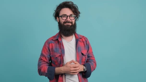 Portré szakállas jóképű fiatalember, hogy mosolyog a türkiz háttér — Stock videók