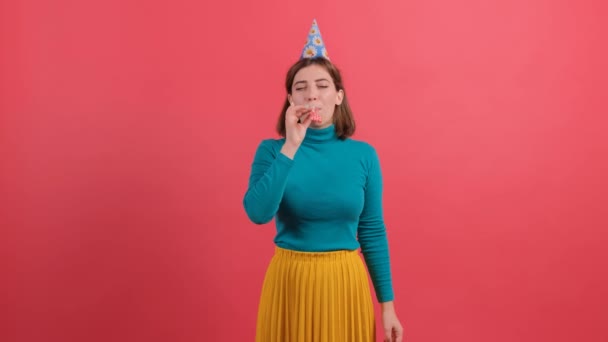 Femme en chapeau d'anniversaire souffle dans la pipe, célébrer, sur fond rouge. — Video