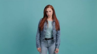 Sıkılmış genç bir kadın, el hareketleriyle vıdı vıdı yapıyor, turkuaz arka planda soyutlanmış..