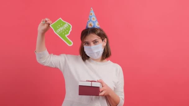 Frau mit medizinischer Maske im Gesicht zeigt mit einem Pappfinger auf die Geschenkbox. — Stockvideo