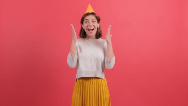 Jeune femme excitée en chapeau d'anniversaire posant isolé sur fond rouge. — Video