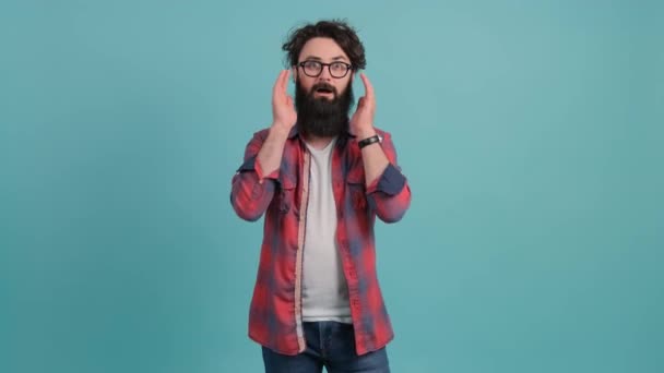 Young bearded man showing surprise and amazed expression with hands on face. — Stock Video