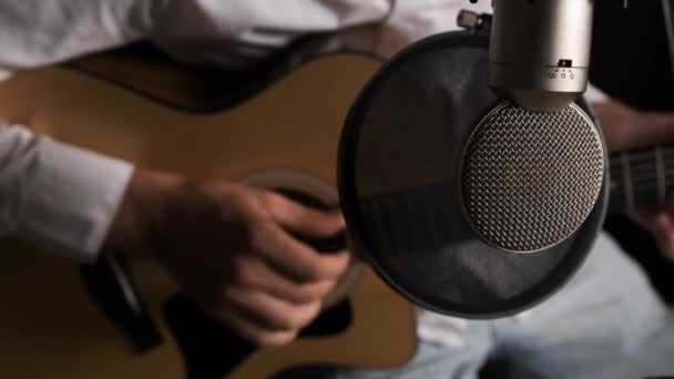 Primo piano di un giovane chitarrista che sta registrando una nuova canzone in uno studio sonoro. — Video Stock