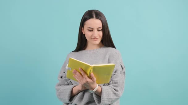 Bella donna carina lettura libro isolato su sfondo turchese. — Video Stock