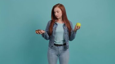 Elma ve donut arasında seçim yapan genç bir kadın, kızın seçiminde kafası karışık.