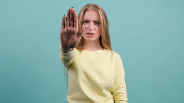 Close up of young woman making stop gesture with her hand, isolated on a turquoise background. — Stock Video