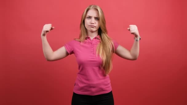 Mujer joven señala las manos fuertes sobre un fondo rojo. — Vídeo de stock