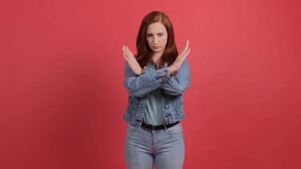 若い女性は、赤い背景に隔離された彼女の手を横断し、停止ジェスチャーを作る. — ストック動画