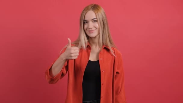 Πορτρέτο της ελκυστική νεαρή γυναίκα δείχνει τους αντίχειρες επάνω στο κόκκινο φόντο — Αρχείο Βίντεο