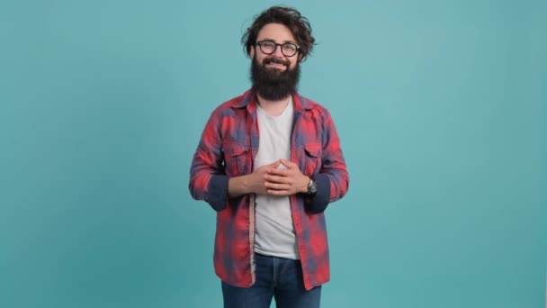 Портрет бородатого красивого молодого человека, улыбающегося на бирюзовом фоне — стоковое видео