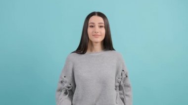Sıkılmış kadın, elinde vıdı vıdı jest yapıyor, turkuaz arka planda soyutlanmış..
