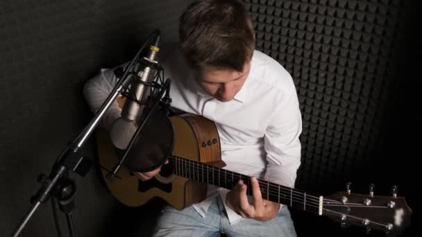 Jovem músico que está gravando nova música em um estúdio de som moderno. — Vídeo de Stock