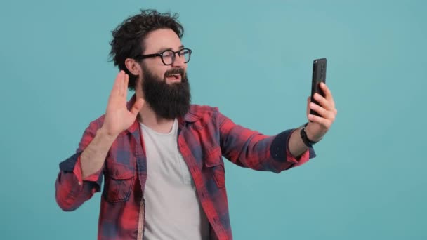 Portret van een man met een baard in gesprek op video en zwaaiend met de hand.. — Stockvideo