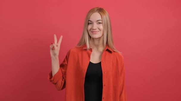 Joven sonriente mostrando signo de paz sobre fondo rojo. — Vídeo de stock