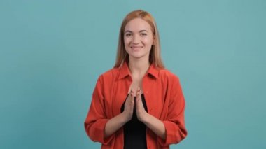 Sarışın güzel kız turkuaz arka planda otururken alkışlıyor..