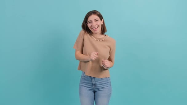 Junge schöne Frau tanzt und posiert vor türkisfarbenem Hintergrund. — Stockvideo