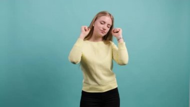 Genç, güzel bir kadın dans ediyor ve turkuaz arka planda poz veriyor..