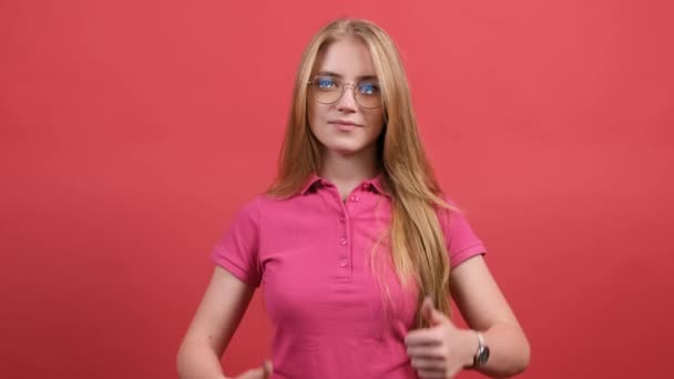 Portret atrakcyjnej młodej kobiety z kciukami w górze na czerwonym tle — Wideo stockowe