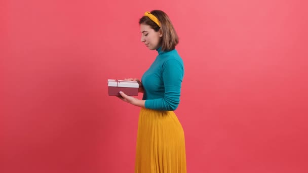 Portrait de femme heureuse ouvrant boîte cadeau sur fond rouge. — Video