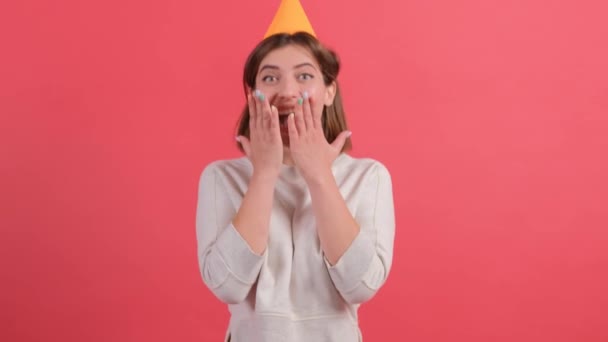 Spændt ung kvinde i fødselsdagshat udgør isoleret på rød baggrund. – Stock-video