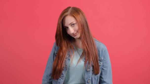 Mujer joven positiva mirando a la cámara con una sonrisa, sobre fondo rojo. — Vídeos de Stock