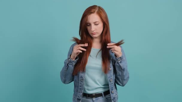 Smutná mladá žena dotýká poškozené vlasy, obává se vypadávání vlasů. — Stock video