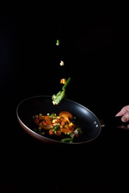 dondurucu hareket. Sebzeler bir tavada, sade bir anahtarda. Vejetaryen yemekleri pişirmek. tatlı biber, mısır, bezelye, soğan, jalapeno, kuşkonmaz fasulyesi. Reklam afişi. Otel, restoran menüsü tasarım konsepti.