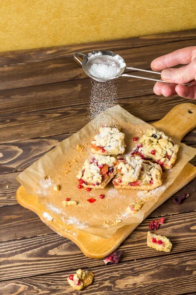 Tasty breakfast. the cook sprinkles icing sugar on the cake. sliced homemade grated pie with berries on a wooden board. large pieces of cake. Hibiscus drink in a transparent cup.