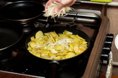 Şef patatese doğranmış soğan ekler. Yemek pişirme. Evde yemek pişir. Tek başına yemek yapmak.