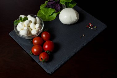 Yemek Geçmişi. Fesleğen yaprağı, marul, domates ve acı biberli büyük ve küçük mozzarella peyniri topları. Eski arka planda. Bedava fotokopi. Üst Manzara. menü tasarımı kavramı