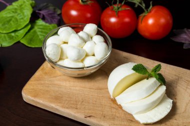  Yemek Geçmişi. Tahta bir tabakta fesleğen, domates ve acı biberle dilimlenmiş büyük bir mozzarella peyniri topu. Eski arka planda. Bedava fotokopi. Üst Manzara. menü tasarımı kavramı